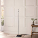 Caldmere Ikat Floor Lamp in Natural, shown without shade, featuring a slim matt black metal stem on a square stepped base, styled in a hallway.