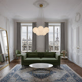 Elegant Parisian living room with a green sofa, round white coffee table, large mirror, and tall windows framing the Eiffel Tower. The Auriel 7 Light Alabaster Chandelier in Soft White & Brushed Brass elevates the sophisticated decor.