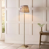 Caldmere Ikat Floor Lamp in Grey, with antique brass metal stem and square base, pleated grey patterned fabric shade, shown in a panelled living room setting.
