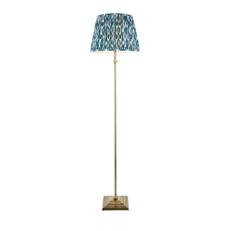 Endon Caldmere floor lamp with antique brass stem and stepped square base, topped with a pleated marlin blue Ikat fabric shade on a white background.