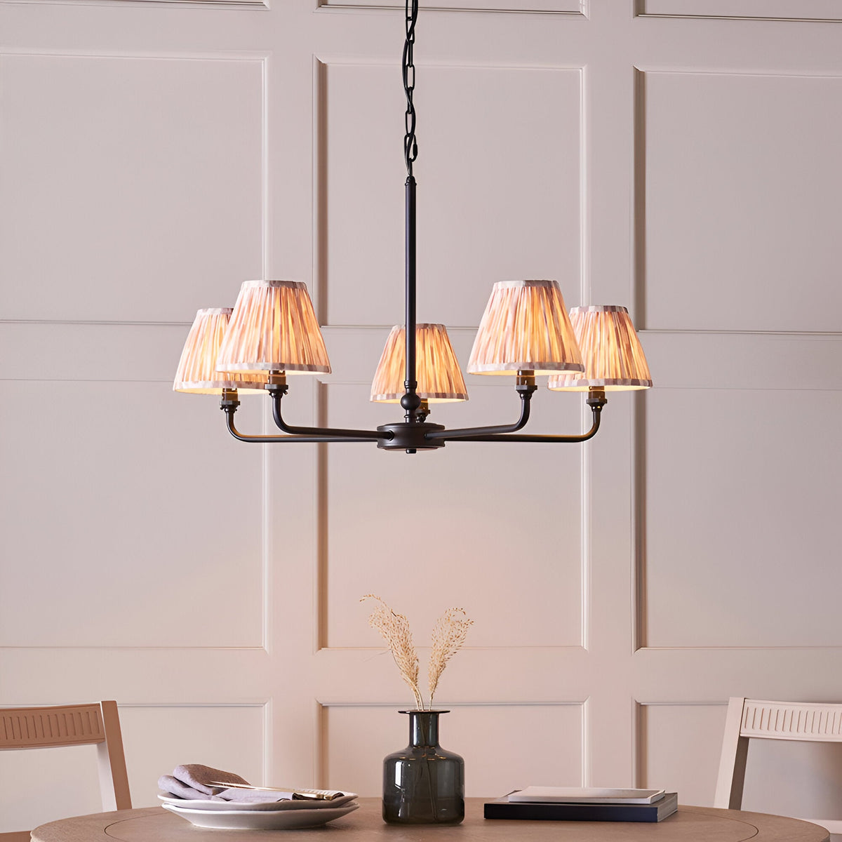 Caldmere 5 Light Ikat Pendant in Natural, with pleated fabric taper shades on a matt black metal frame, hung above a dining table.