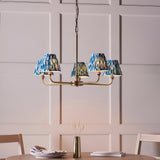 Endon Caldmere 5 light pendant with tapered pleated marlin blue ikat fabric shades on antique brass arms, hung above a dining table.