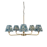 Endon Caldmere five light pendant with tapered pleated ikat shades in marlin blue on antique brass arms, suspended from a chain on a white background.