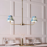 Endon Caldmere 2 light pendant with tapered blue ikat fabric shades on an antique brass linear frame, shown above a dining table.