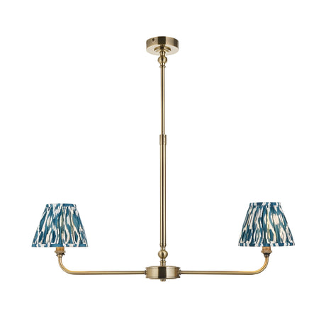 Endon Caldmere 2 light pendant with tapered pleated blue ikat fabric shades on a linear antique brass telescopic stem, on a white background.