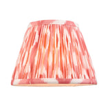 Caldmere Ikat Wall Light in coral shows a pleated tapered fabric shade with pink and orange ikat pattern and cream trim, shown against a plain white background.