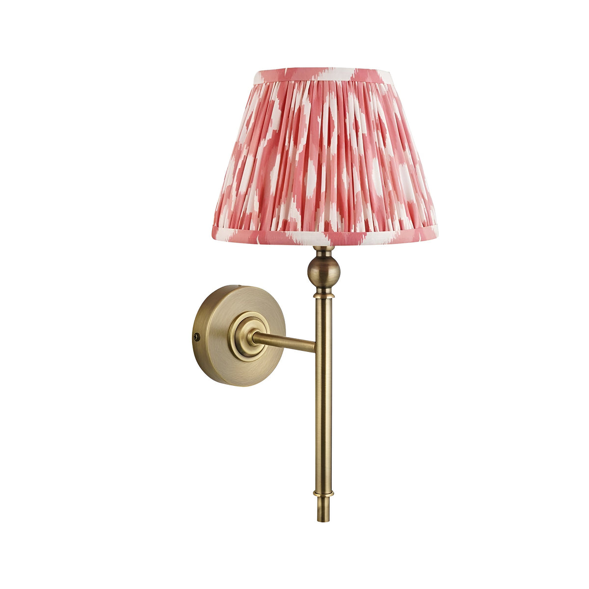 Caldmere Ikat Wall Light in Coral, with a pleated coral pink patterned shade on an antique brass wall arm and circular backplate.