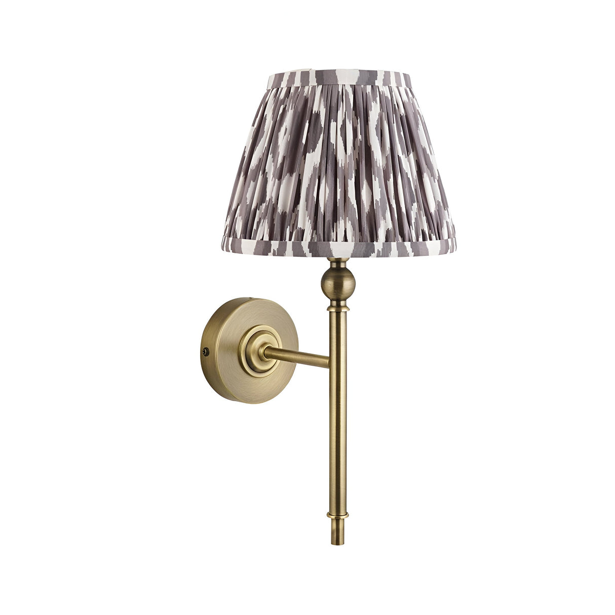 Endon Caldmere wall light with tapered pleated grey Ikat fabric shade on a slim antique brass arm and round wall plate, on a white background.