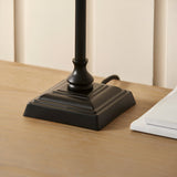 Close-up of the Endon Caldmont table lamp's stepped square base and turned column in matt black, resting on a light wood surface.