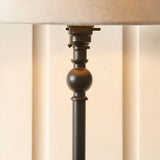 Endon Caldmont table lamp close-up showing matt black candlestick column with turned ball detail, switched B22 holder, and natural linen shade.