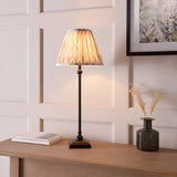 Caldmere Ikat Table Lamp in Cream with pleated fabric shade on a matt black candlestick-style base, shown lit on a wooden console table.