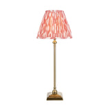 Caldmere Ikat Table Lamp in coral with a pleated fabric shade and slim antique brass candlestick base on a square footed plinth.