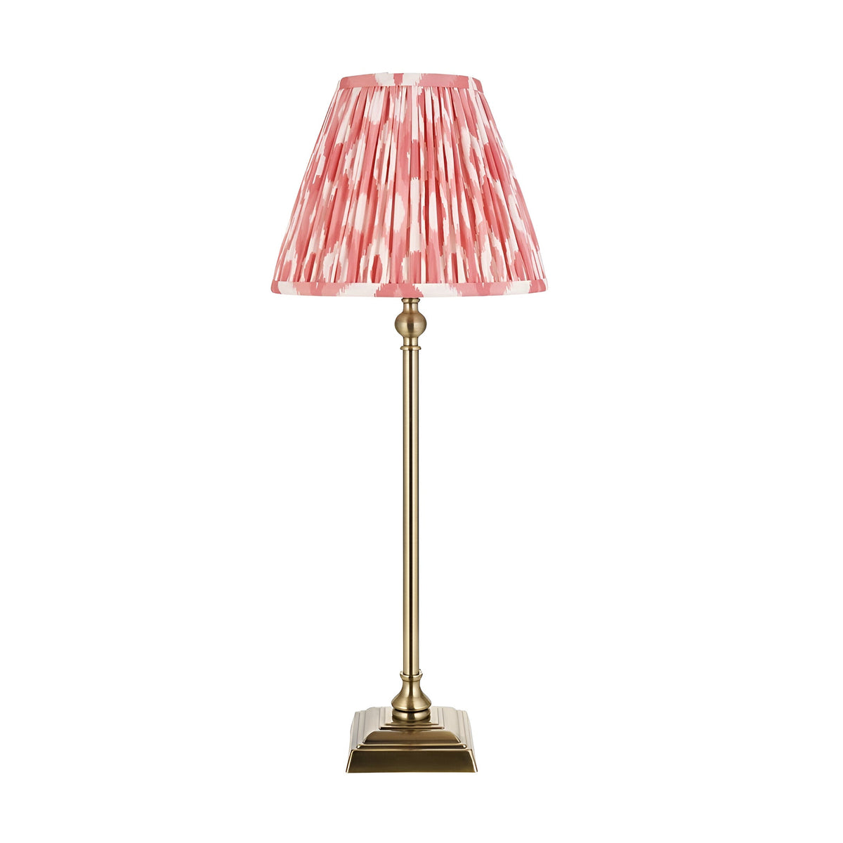 Caldmere Ikat Table Lamp in coral, featuring an antique brass candlestick base with slim turned stem and pleated coral-and-white patterned fabric shade.