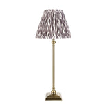 Endon Caldmere table lamp with slim antique brass candlestick base and pleated grey Ikat print fabric shade, shown on a plain white background.