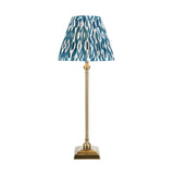 Endon Caldmere table lamp with slim antique brass candlestick stand and pleated blue ikat-print fabric shade, shown on a plain white background.
