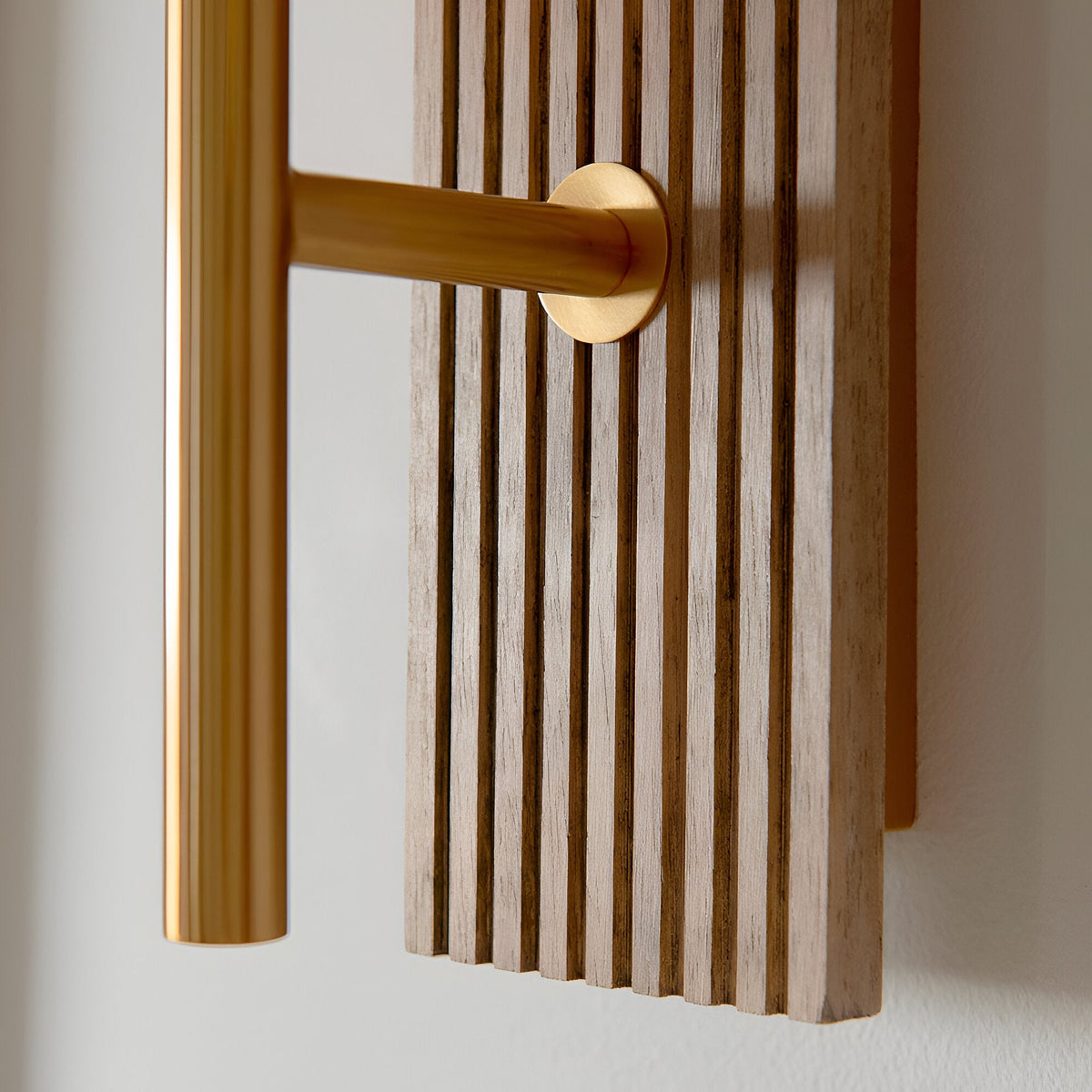 Bramton Wall Light in brass, close-up of the vintage brass arm and circular wall mount against a grooved walnut-stained beechwood backplate.