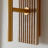 Bramton Wall Light in brass, close-up of the vintage brass arm and circular wall mount against a grooved walnut-stained beechwood backplate.