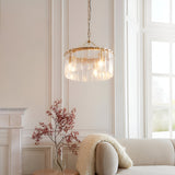 Brockhurst 3 Light Pendant in brass with textured clear glass panels, hung from a chain in a light-toned living room above a sofa.