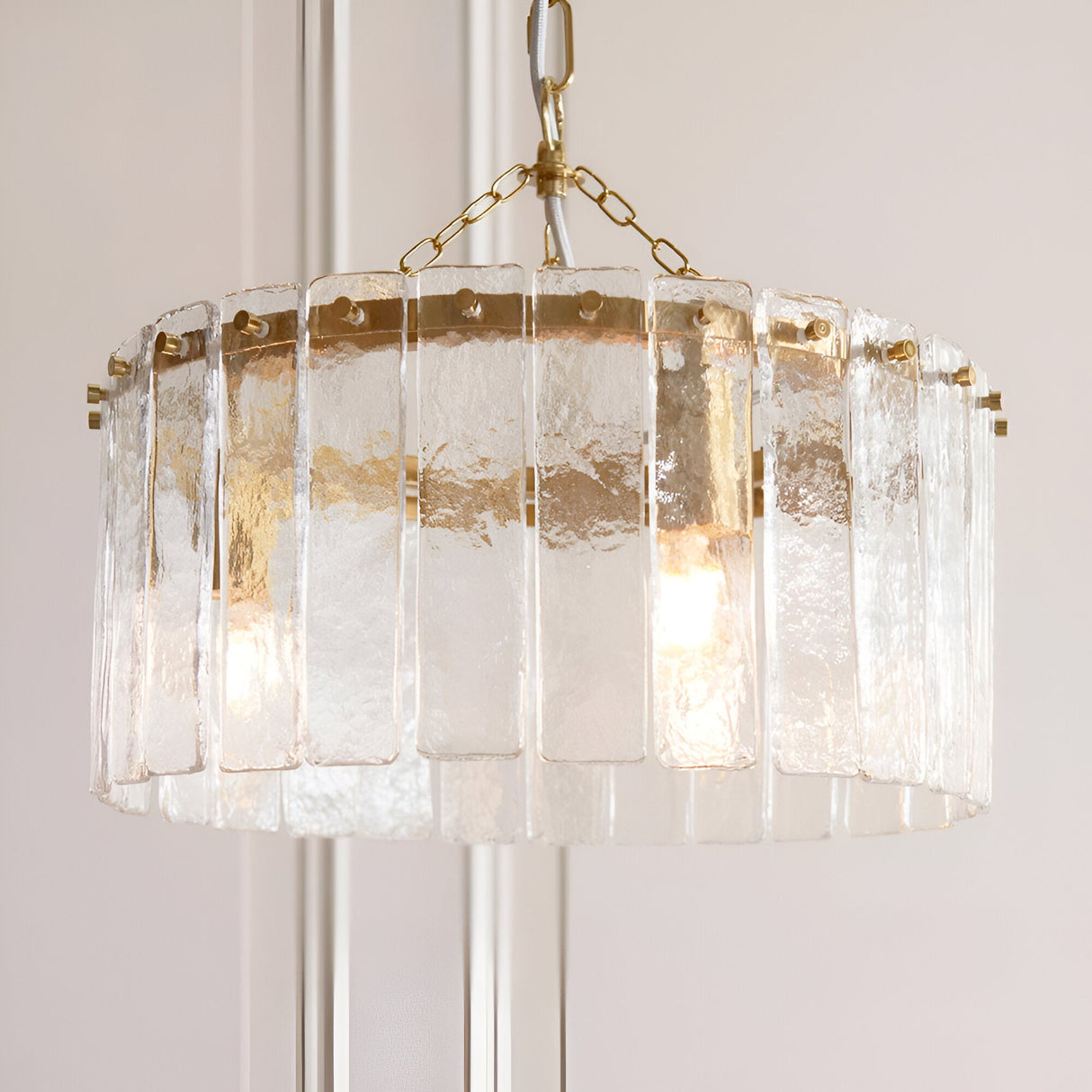 Brockhurst 3 Light Pendant in Brass, drum-shaped fixture with vertical textured glass panels around a brass band, hung from a brass chain.