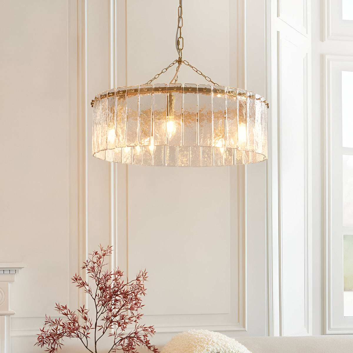 Endon Brockhurst 5 light pendant in brushed aged brass with textured glass panels in a drum ring, hanging from a chain in a bright panelled room.
