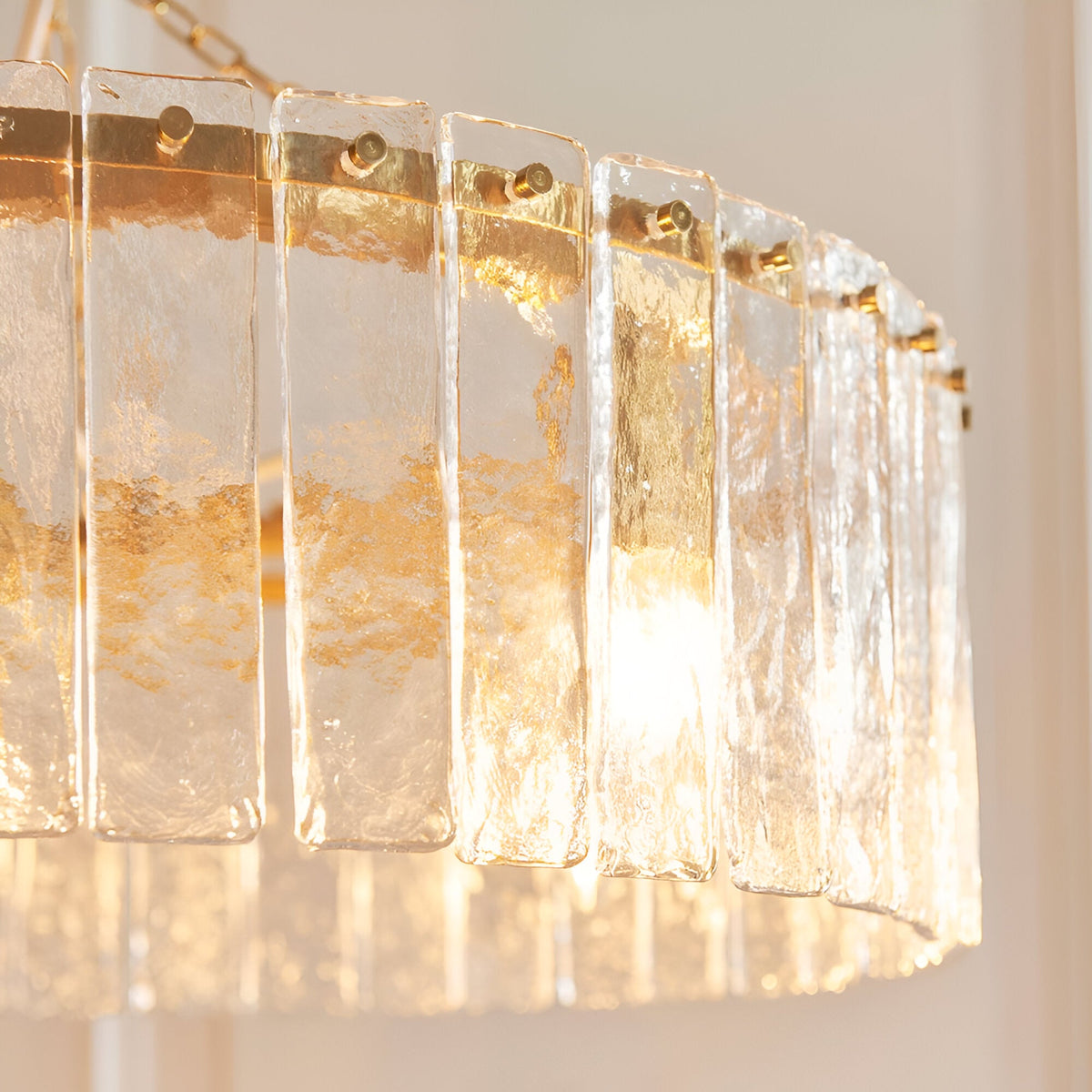 Close-up of the Endon Brockhurst 5 light pendant showing handmade textured glass panels fixed to a brushed aged brass frame with warm illumination.