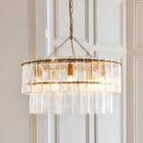Endon Brockhurst 5 light chandelier in brushed aged brass with two tiers of textured glass panels, suspended from a chain against pale panelled doors.