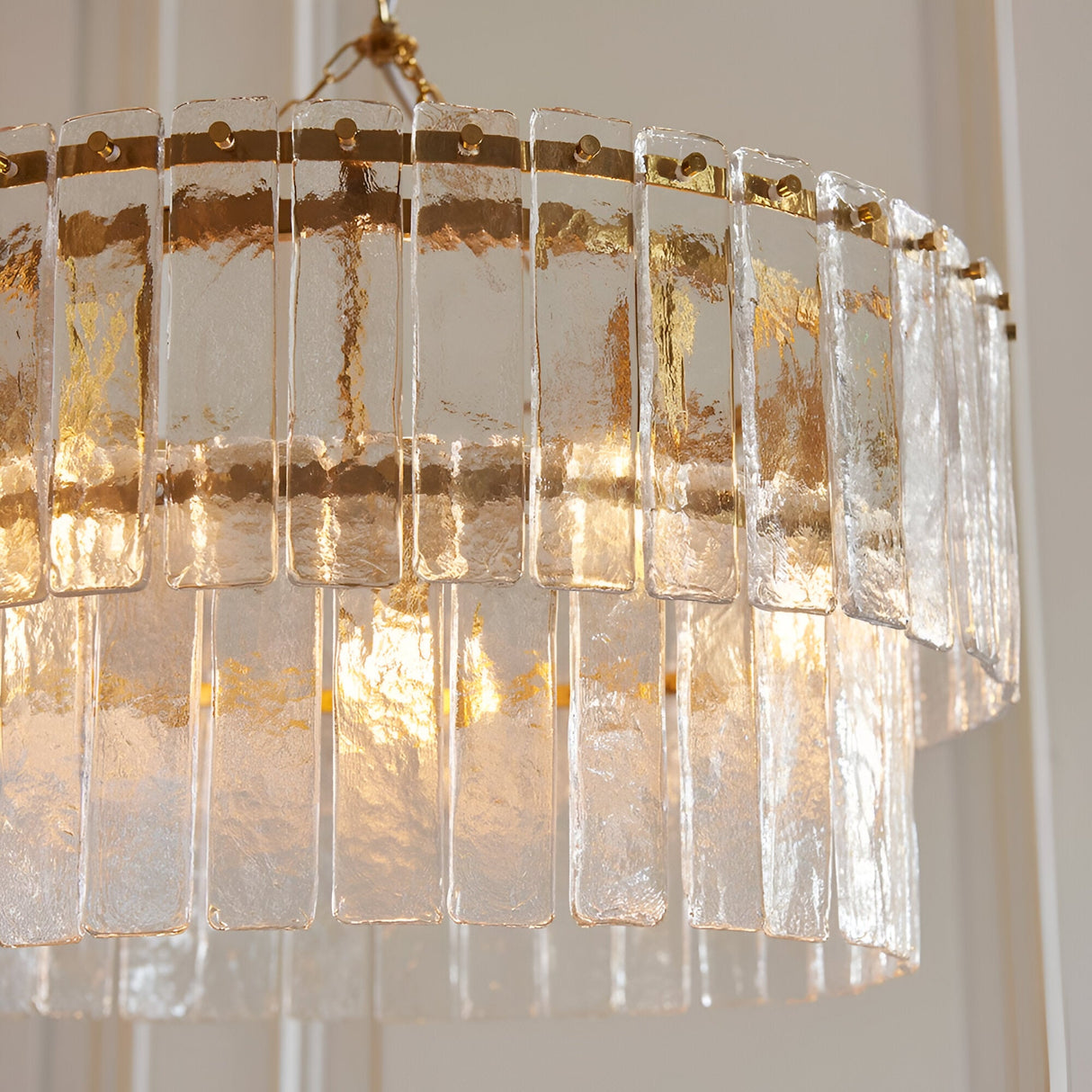 Endon Brockhurst 5 light chandelier in brushed aged brass with two tiers of textured rectangular glass panels, illuminated close-up view.
