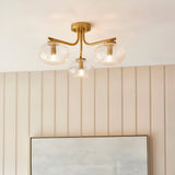 Pemberton 3 Light Semi-Flush Ceiling Light in brass with clear bubble glass shades, shown on a panelled wall above framed artwork.