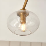 Pemberton 3 Light Semi-Flush Ceiling Light in brass, close-up of one seeded glass globe shade with lit bulb on a brass stem against a plain white background.