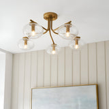 Endon Pemberton 5 light semi-flush ceiling light in brass with clear glass globe shades, installed above a framed artwork in a panelled room.