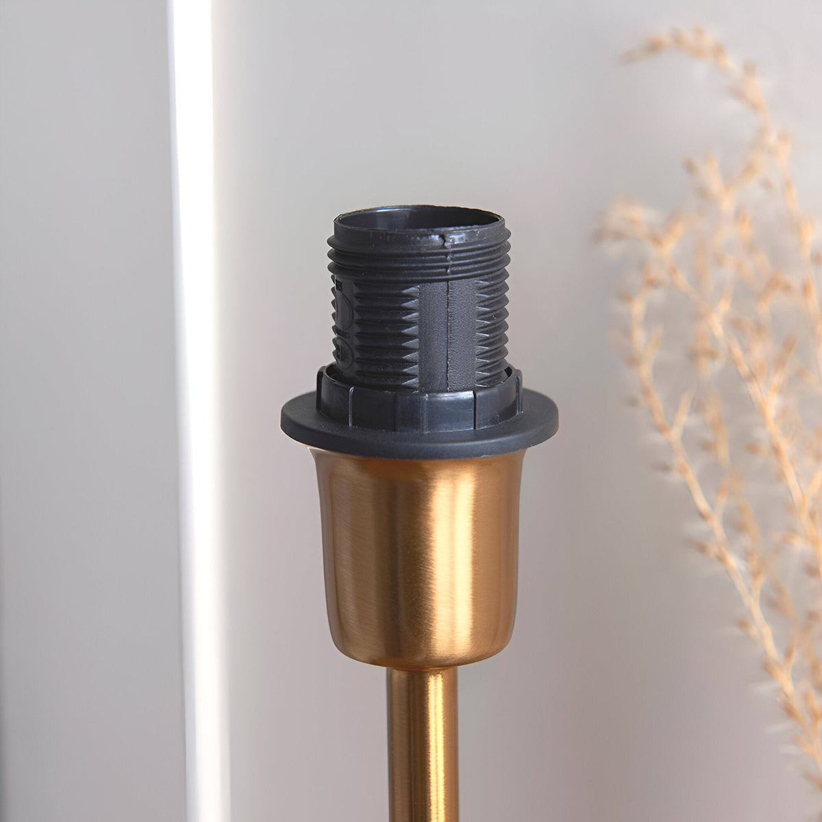 Close-up of the Endon Chartworth table lamp brass base showing the E14 bulb holder and brushed brass stem against a soft neutral background.