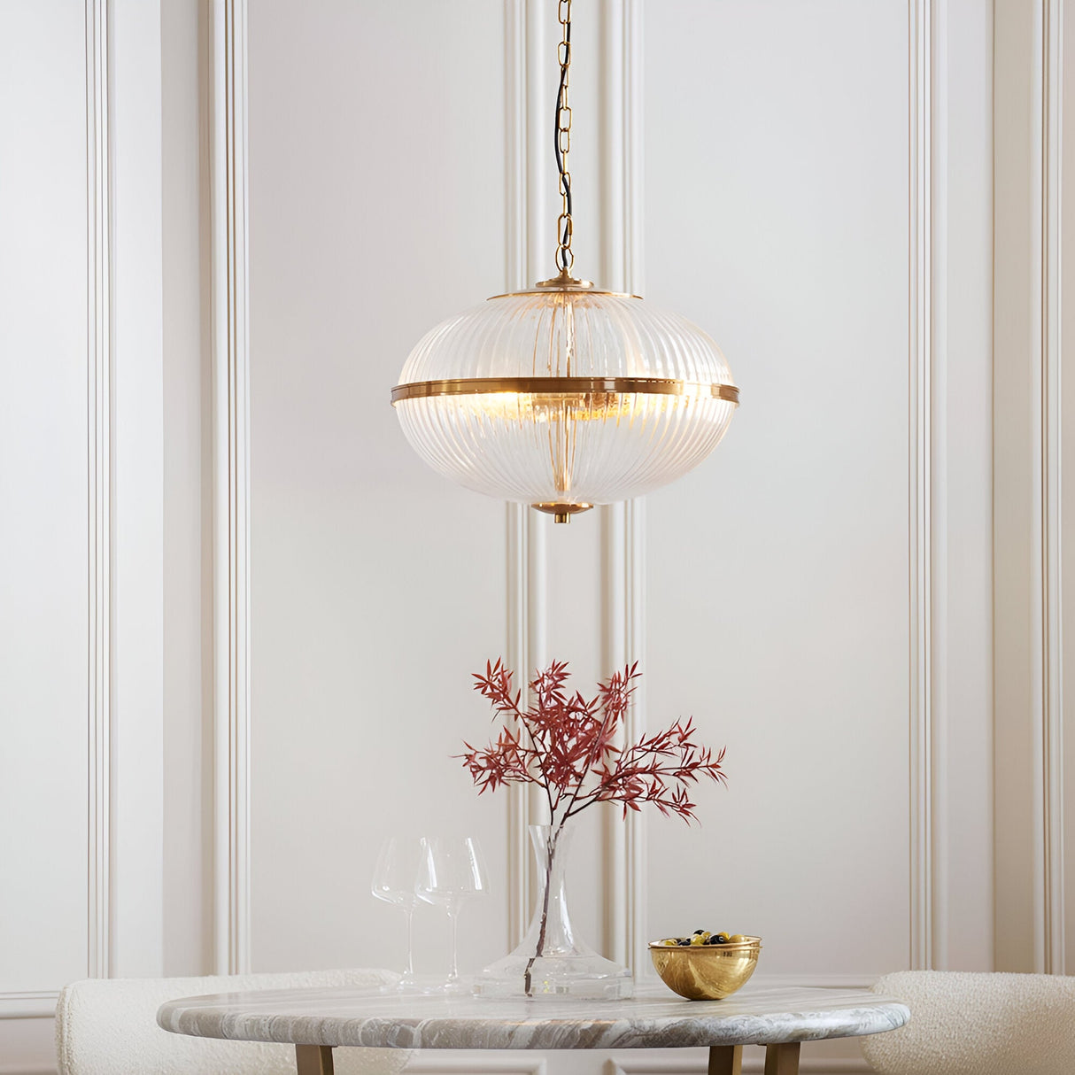 Langton 3 Light Pendant in Brass with ribbed glass globe on a chain, hanging above a dining table in a panelled room.