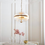 Langton 3 Light Pendant in brass with ribbed glass globe on chain, hanging in a panelled dining room above a table setting.