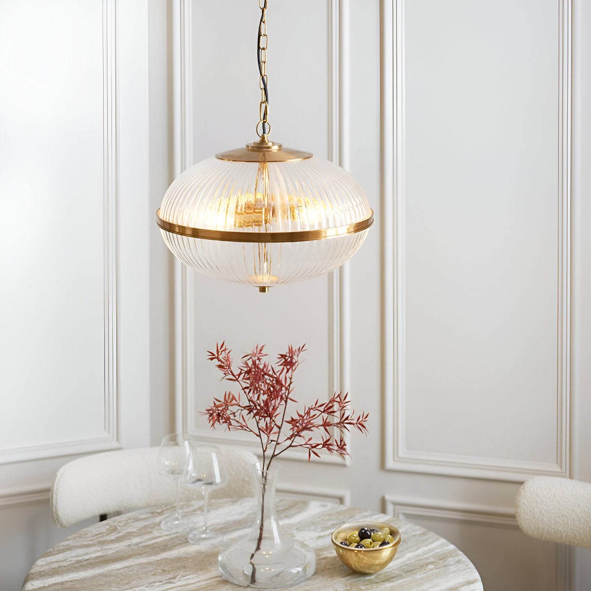 Langton 3 Light Pendant in brass with ribbed glass globe, hanging above a dining table in a light-panelled room.