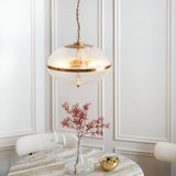 Langton 3 Light Pendant in brass with ribbed glass globe, hanging above a dining table in a light-panelled room.