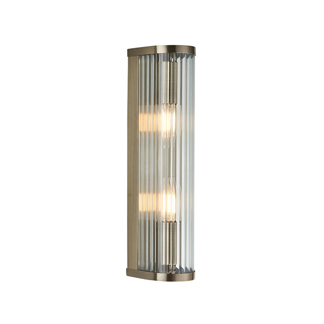 Rothbury 2 Light Wall Light in antique brass with vertically ribbed clear glass diffusers, shown lit against a plain white background.
