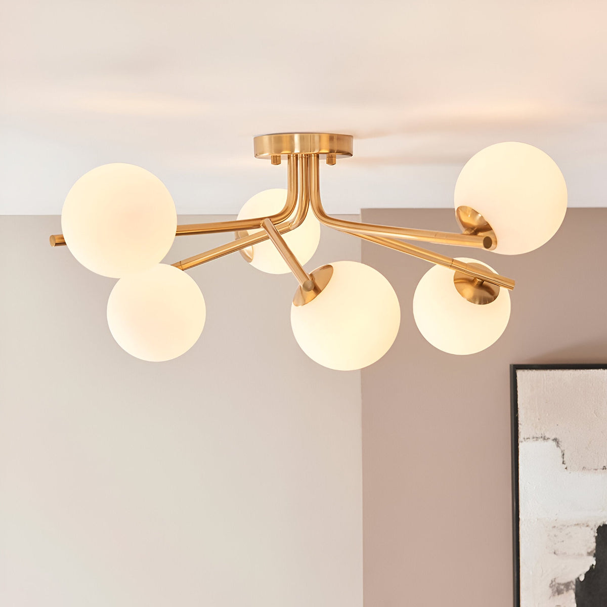 Grantham 6 Light Semi-Flush Ceiling Light in aged brass with round opal glass globes on branching arms, shown mounted on a living room ceiling.