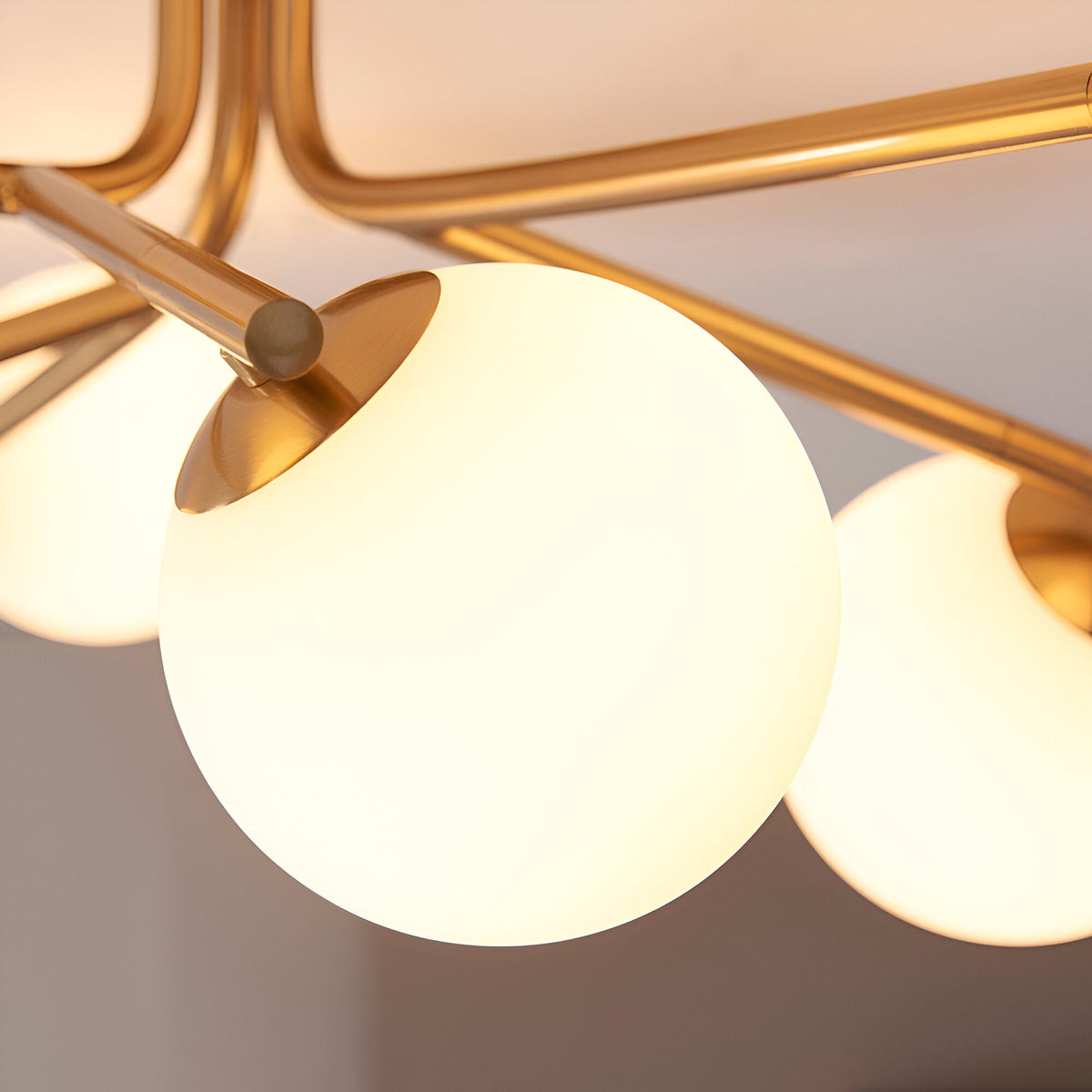 Close-up of the Grantham 6 Light Semi-Flush Ceiling Light, showing aged brass arms and round opal glass globe shades against a pale ceiling.