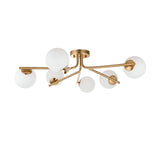 Grantham 6 Light Semi-Flush Ceiling Light in aged brass, with six angled arms holding round white glass globe shades, shown on a plain white background.