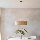 Endon Salcombe pendant light with woven natural seagrass drum shade and matt black cable, hung above a dining table in a neutral room.