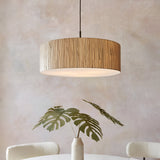 Endon Salcombe 3 light pendant with woven natural seagrass drum shade and matt black cable, hung above a monstera arrangement in a neutral dining room.