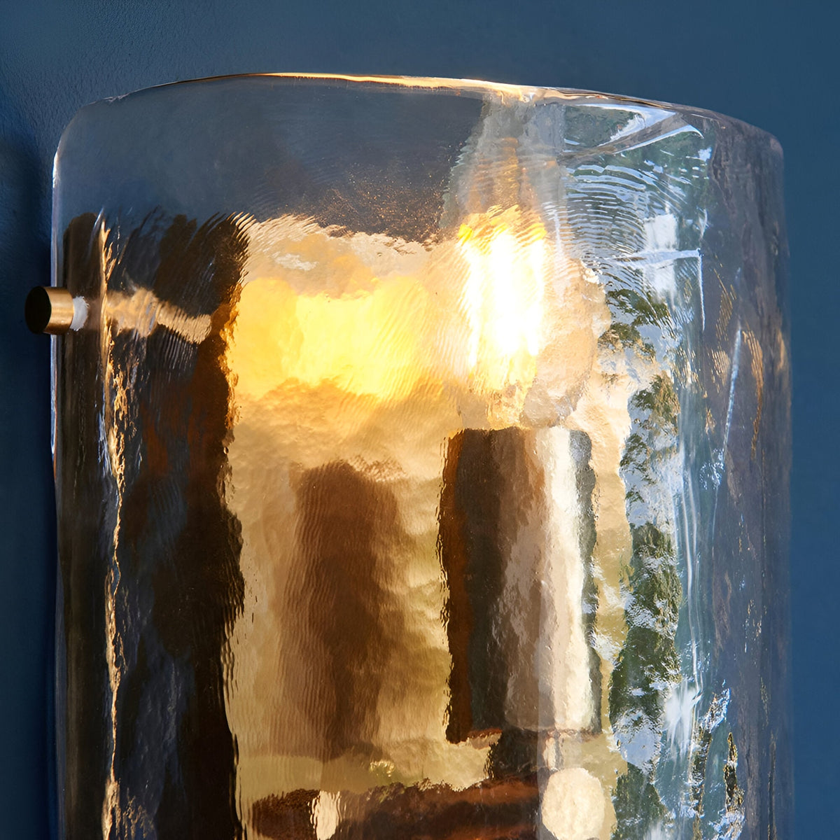 Endon Brockmont 2 light wall light with curved handmade textured glass panel illuminated in warm tones against a deep blue wall.