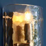 Endon Brockmont 2 light wall light with curved handmade textured glass panel illuminated in warm tones against a deep blue wall.