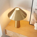 Endon Brockbourne table lamp in brushed antique brass with a wide conical shade and tapered base, styled on an oak console beside a framed print.