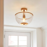 Endon Langton flush uplighter in brass with ribbed glass bowl diffuser and single E27 lamp, mounted on a white ceiling above an interior doorway.