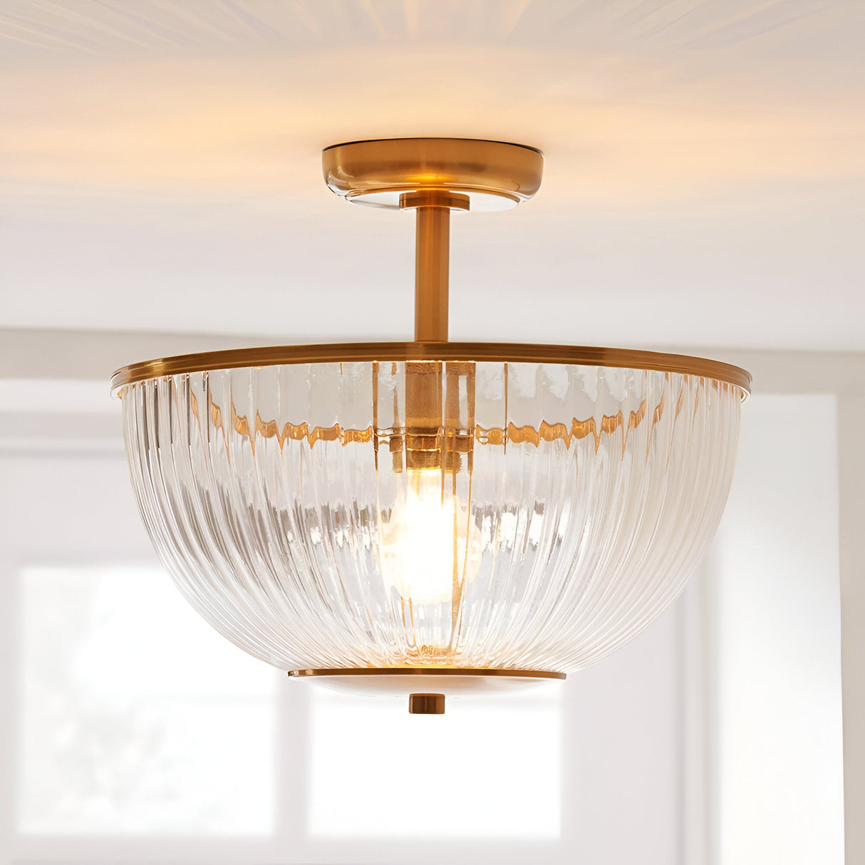 Endon Langton flush uplighter with brass fitting and ribbed clear glass bowl diffuser, mounted to a white ceiling near a bright window.
