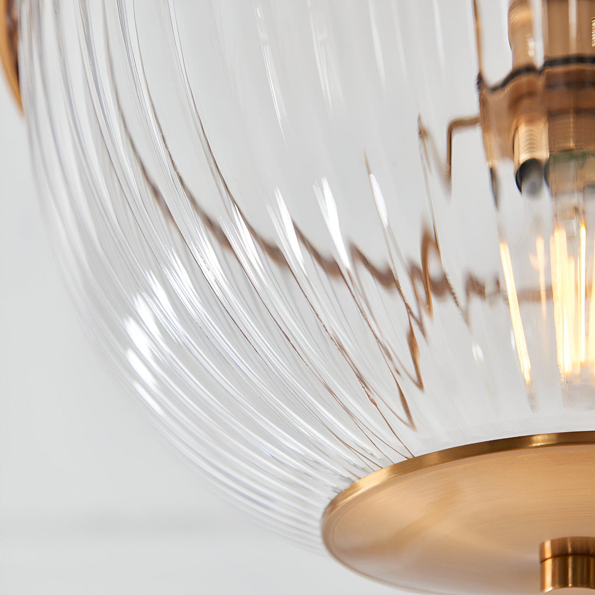 Close-up of the Endon Langton flush uplighter showing its ribbed clear glass diffuser and brass fittings around the E27 lamp holder.