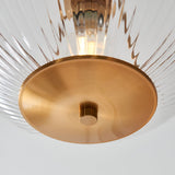 Close-up of the Endon Langton Flush Uplighter showing its brushed brass base, ribbed clear glass diffuser and illuminated E27 lamp within.