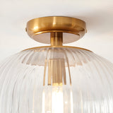 Langton Flush Downlight in brass with a ribbed glass globe shade and single E27 lamp, close-up view against a plain white ceiling.