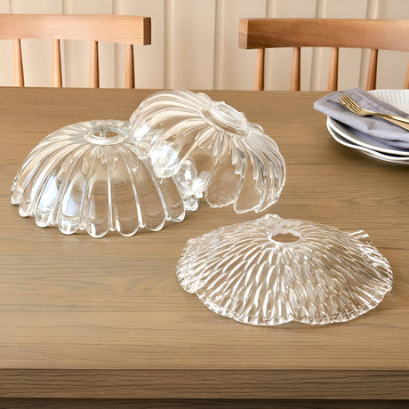 Three Endon Castshaw clear glass easyfit pendant shades with rippled, shell-like textures displayed on a wooden dining table beside plates and cutlery.